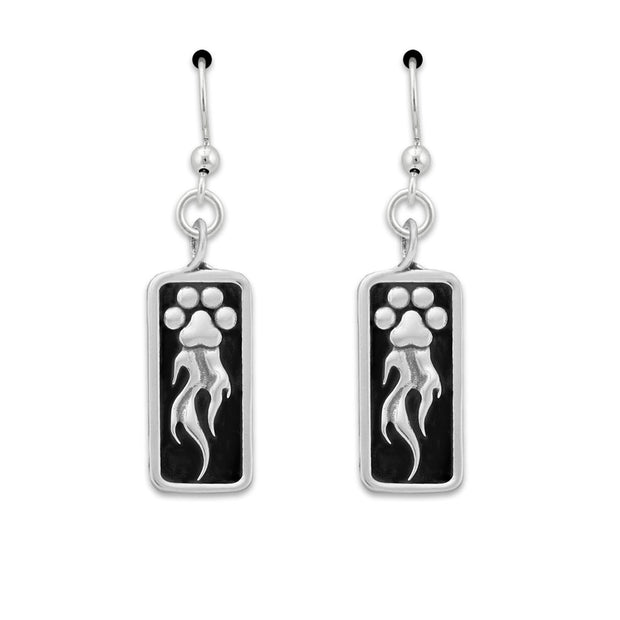 A pair of sterling silver earrings featuring a paw print design with flames shooting off it, attached to a rectangular black background.