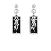 A pair of sterling silver earrings featuring a paw print design with flames shooting off it, attached to a rectangular black background.